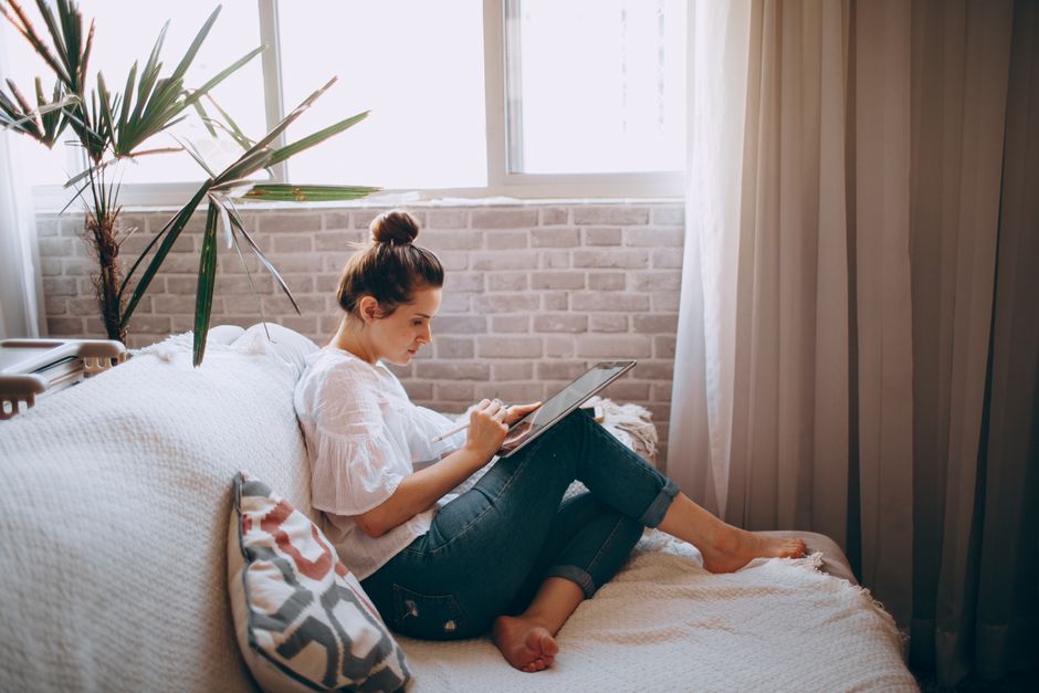Professional real estate agent stands in a bright, modern living room, showcasing property details on a digital tablet.