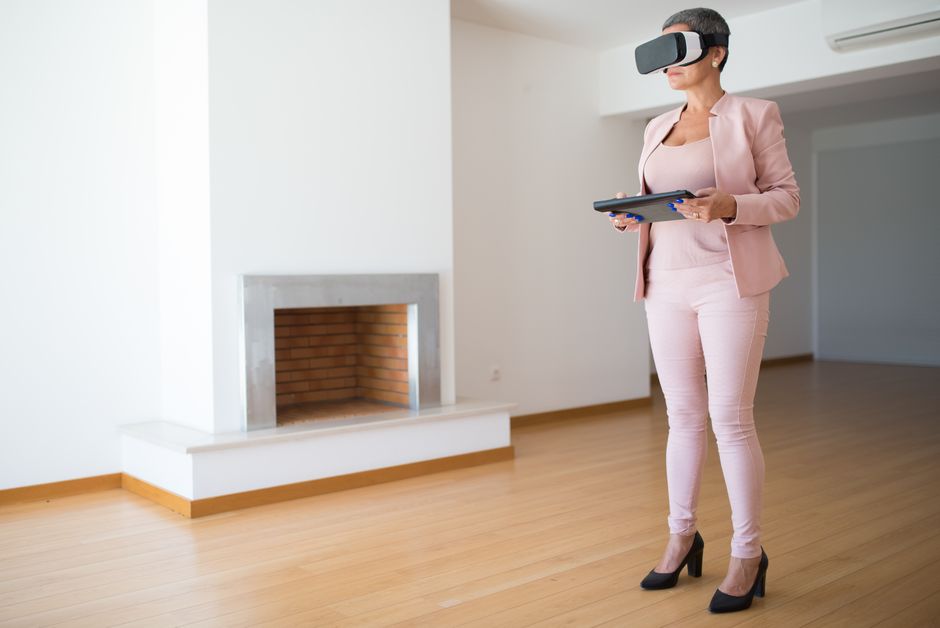 Professional real estate agent stands in a bright, modern living room, showing clients information on a digital tablet.
